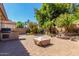 Large backyard with pavers, an outdoor kitchen, a waterfall feature, and lush landscaping at 2680 E Lodgepole Dr, Gilbert, AZ 85298
