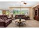 Comfortable living room area featuring a ceiling fan, carpet flooring, and large windows at 2680 E Lodgepole Dr, Gilbert, AZ 85298