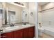 A full bathroom showcases double sinks, granite counters, cherry vanity and tub with shower at 3485 S Seneca Way, Gilbert, AZ 85297