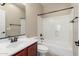 Bright bathroom featuring a tub, shower, dark hardware, cherry vanity and framed mirror at 3485 S Seneca Way, Gilbert, AZ 85297