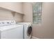 Laundry room offers open shelving, tile floors, and a bright window at 3485 S Seneca Way, Gilbert, AZ 85297