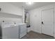 A laundry room with a washer, dryer, water heater, shelving, and a door to the left at 3802 W Mission Ln, Phoenix, AZ 85051