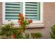 Closeup of the home's exterior showing a window with light shutters and vibrant orange flowers at 4020 N 151St Dr, Goodyear, AZ 85395