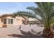 Expansive backyard featuring a gravel groundcover with a paved patio, complemented by lush palm trees and vibrant desert landscaping at 41341 W Little Dr, Maricopa, AZ 85138