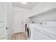 Convenient laundry room featuring modern washer and dryer units, storage shelving, and a utility sink at 41341 W Little Dr, Maricopa, AZ 85138