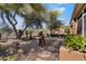 Landscaped backyard featuring decorative metal sculptures, mature trees, and desert vegetation at 41910 N Long Cove Way, Anthem, AZ 85086