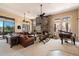Open-concept living room with stone fireplace, leather sofa, and access to the backyard at 41910 N Long Cove Way, Anthem, AZ 85086