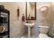 Elegant powder room featuring a pedestal sink, tiled walls, and decorative lighting at 41910 N Long Cove Way, Anthem, AZ 85086