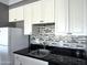 Close up of the kitchen featuring white cabinets, sleek black countertops, and mosaic backsplash at 4750 N Central Ave # M2, Phoenix, AZ 85012
