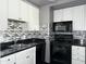 Close up of the kitchen featuring sleek black countertops, black appliances, and mosaic backsplash at 4750 N Central Ave # M2, Phoenix, AZ 85012