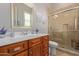 Classic bathroom featuring a wood vanity with a white countertop, a tiled shower with a glass door, and soft accents at 6125 E Hodges St, Cave Creek, AZ 85331