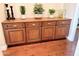 A spacious, wood cabinet with four doors sits atop wood flooring and features stylish plants on the surface at 6125 E Hodges St, Cave Creek, AZ 85331