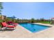 Beautiful pool with red chaise lounges and umbrellas surrounded by lush landscaping and desert views at 6125 E Hodges St, Cave Creek, AZ 85331