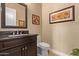 Elegant powder room featuring dark vanity, granite countertop, framed mirror, and beautiful floral artwork at 6125 E Hodges St, Cave Creek, AZ 85331