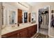 Spacious bathroom with double vanity, wooden cabinetry, large mirror and an adjacent walk-in closet at 6441 E Colby St, Mesa, AZ 85205