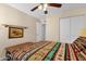 Cozy bedroom featuring a patterned bedspread, ceiling fan, neutral walls and a side door at 6441 E Colby St, Mesa, AZ 85205