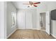 Simple bedroom with vinyl floors, a ceiling fan, large window, closet, and door to the hallway at 6920 W Via Montoya Dr, Glendale, AZ 85310