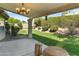 A covered patio with a chandelier overlooks a manicured backyard with lush greenery at 6920 W Via Montoya Dr, Glendale, AZ 85310
