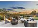 Cozy outdoor seating area with comfortable chairs, a coffee table, and lush landscaping with sunset in the background at 8245 E Via Del Sol Dr, Scottsdale, AZ 85255