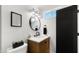 Modern bathroom with wood vanity, dark fixtures, and a round mirror, creating a contemporary and stylish space at 8631 E Jackrabbit Rd, Scottsdale, AZ 85250