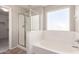 The bathroom has a clear glass shower, soaking tub and a large window allowing for natural light to enter at 906 S 242Nd Dr, Buckeye, AZ 85326