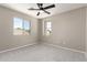 Bright bedroom featuring neutral walls, carpet flooring, a ceiling fan, and two windows for natural light at 906 S 242Nd Dr, Buckeye, AZ 85326