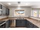 This kitchen features stainless steel appliances, dark cabinets, and tile flooring at 906 S 242Nd Dr, Buckeye, AZ 85326