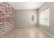 Spacious living room featuring neutral paint, tile flooring, and a charming exposed brick wall at 906 S 242Nd Dr, Buckeye, AZ 85326