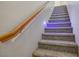 Carpeted staircase featuring a wooden railing and modern recessed lighting on the wall at 935 E Redondo Dr, Gilbert, AZ 85296
