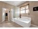 Bathroom featuring a soaking tub, glass block shower, and neutral tile for a spa-like experience at 13827 N Mesquite Ln, Fountain Hills, AZ 85268