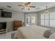 This bedroom offers French doors, white shutters, a ceiling fan and light fixture, and a TV mounted on the wall at 14334 W Shawnee Trl, Surprise, AZ 85374
