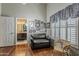 Cozy bedroom with hardwood floors, accent seating, and bathroom access, filled with natural light at 14334 W Shawnee Trl, Surprise, AZ 85374