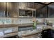 Close-up of kitchen featuring stainless steel microwave, cooktop, tile backsplash, and dark cabinetry at 14334 W Shawnee Trl, Surprise, AZ 85374
