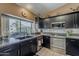 Well-lit kitchen featuring black cabinetry, granite countertops, stainless steel appliances, and backyard view at 14334 W Shawnee Trl, Surprise, AZ 85374