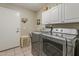 Functional laundry room with modern washer and dryer units, storage cabinets, and tile flooring at 14334 W Shawnee Trl, Surprise, AZ 85374