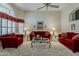 Spacious living room with high ceilings, shuttered windows and comfortable red sofas and armchairs at 14334 W Shawnee Trl, Surprise, AZ 85374