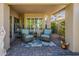 The backyard covered patio area has seating, neutral tones, and privacy landscaping for a tranquil experience at 14334 W Shawnee Trl, Surprise, AZ 85374