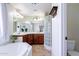 Bathroom featuring a soaking tub, a glass block shower, double sinks with wood cabinets and neutral tile flooring at 1438 E Mesquite St, Gilbert, AZ 85296