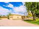 Single-story home with spacious driveway and garage, accented by a lush green lawn, mature trees and stone accents at 1438 E Mesquite St, Gilbert, AZ 85296