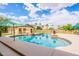 Beautiful backyard pool with an umbrella, surrounded by lush landscaping and clear blue sky with fluffy clouds at 1438 E Mesquite St, Gilbert, AZ 85296