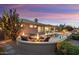 Beautiful backyard with a firepit and heated pool and spa combination at sunset at 15109 W Waterford Dr, Surprise, AZ 85374