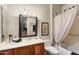 Well-lit bathroom features a vanity with cabinet, decorative mirror, toilet, and shower/tub with curtain at 15109 W Waterford Dr, Surprise, AZ 85374