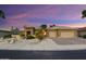 Charming single-story home with desert landscaping, stone accents, and three car garage at dusk at 15109 W Waterford Dr, Surprise, AZ 85374