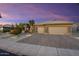 Charming home with desert landscaping, stone accents, paver driveway, and three car garage at dusk at 15109 W Waterford Dr, Surprise, AZ 85374