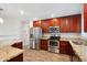Modern kitchen featuring stainless steel appliances, granite countertops, and cherry wood cabinets at 1529 W Rovey Ave, Phoenix, AZ 85015