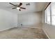 Comfortable bedroom features neutral carpet, a ceiling fan, and natural light from the window at 16188 W Boca Raton Rd, Surprise, AZ 85379