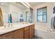 Spacious bathroom featuring dual sinks, wooden cabinets, a soaking tub, and a large mirror at 1633 W Lacewood Pl, Phoenix, AZ 85045