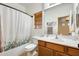 Bright bathroom with a wood vanity, a toilet and a shower/tub combination with a patterned shower curtain at 1633 W Lacewood Pl, Phoenix, AZ 85045