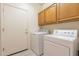 Functional laundry room featuring a side-by-side washer and dryer with overhead cabinets and a utility door at 20627 N Lemon Drop Dr, Maricopa, AZ 85138