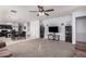 Open-concept living room with a ceiling fan, plush carpeting, and easy access to the kitchen and dining area at 23805 W Romley Ave, Buckeye, AZ 85326